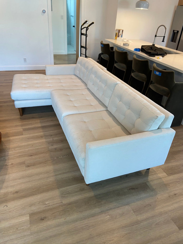 Modern CB2 sectional sofa, cream upholstery and tufting, deep seating, wood legs, gently used, ideal for living rooms.  