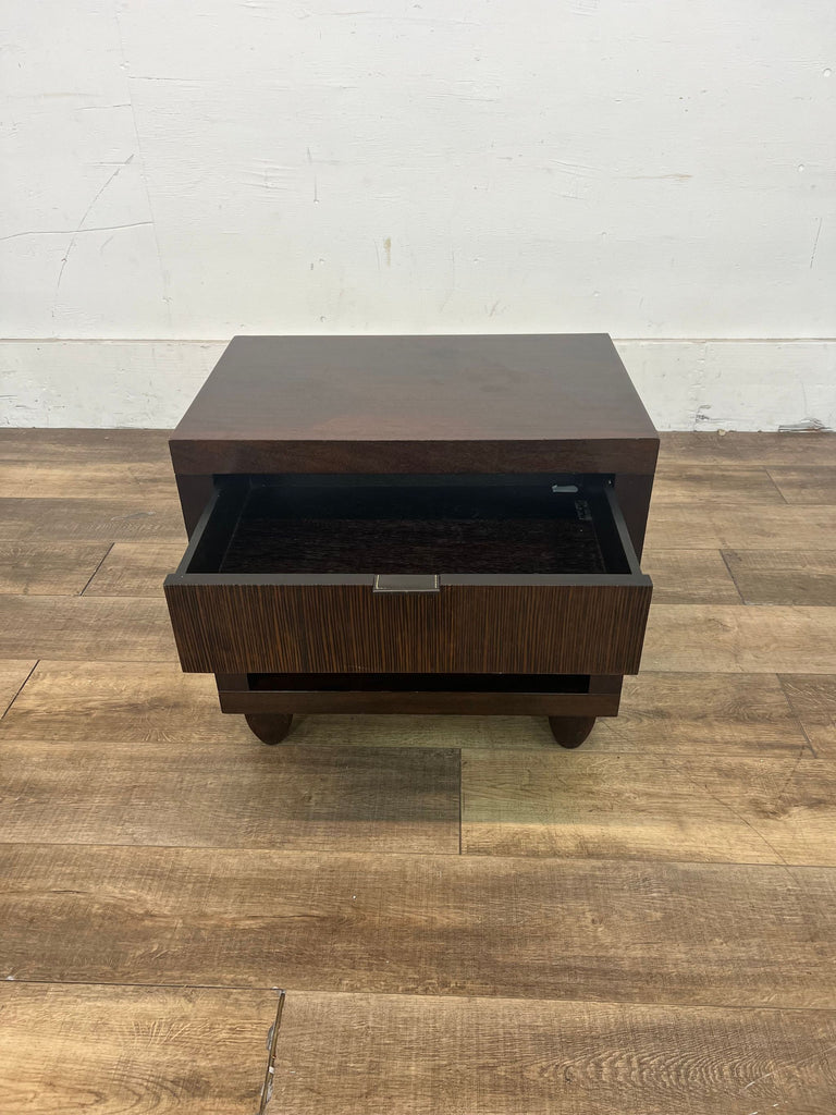 2. Front view of a Reperch end table with its drawer partially open, displaying the wood grain and silver handle, against a simple wall and wood floor backdrop.