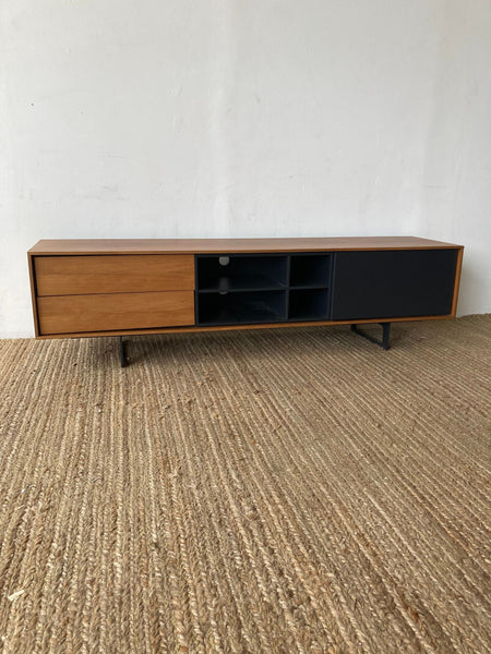 Mid-century modern media unit with wood finish and open shelves on a woven rug.
