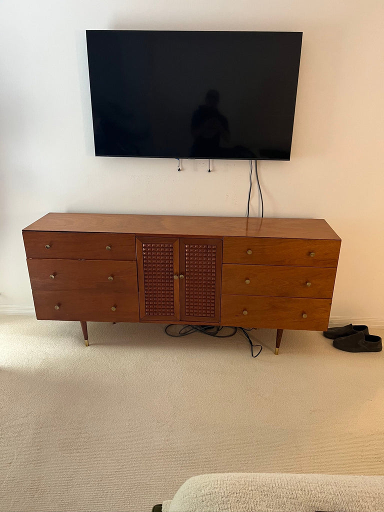 Classic entertainment center in warm wood, with spacious storage drawers, a central cabinet, and stable brass-accented legs.