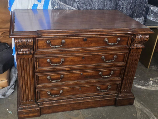 A traditional four-drawer Sligh file cabinet with ornate metal handles and rich wood finish.