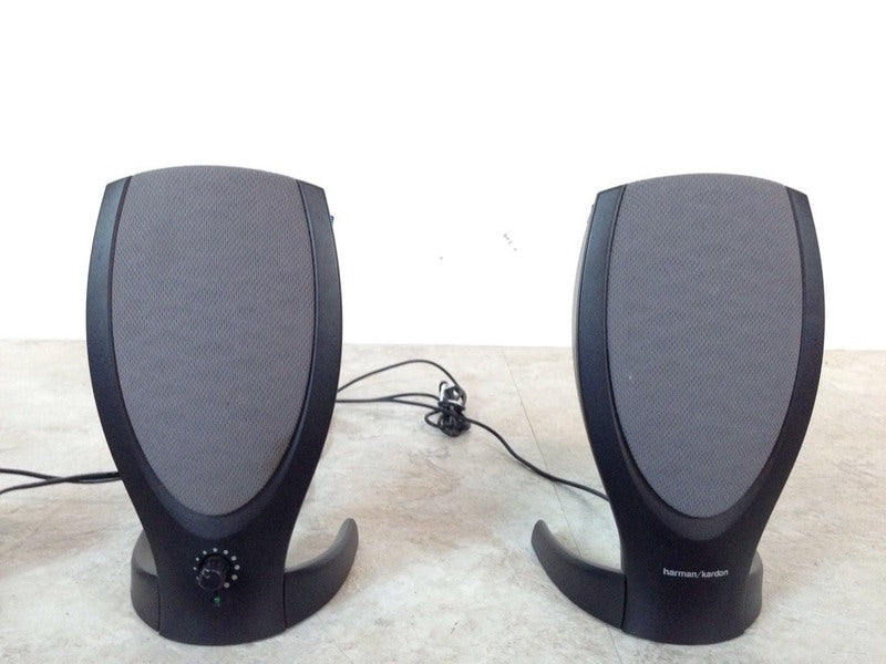 1. Pair of Harman/Kardon speakers with cords included, featuring a sleek, curved design, on a light surface.