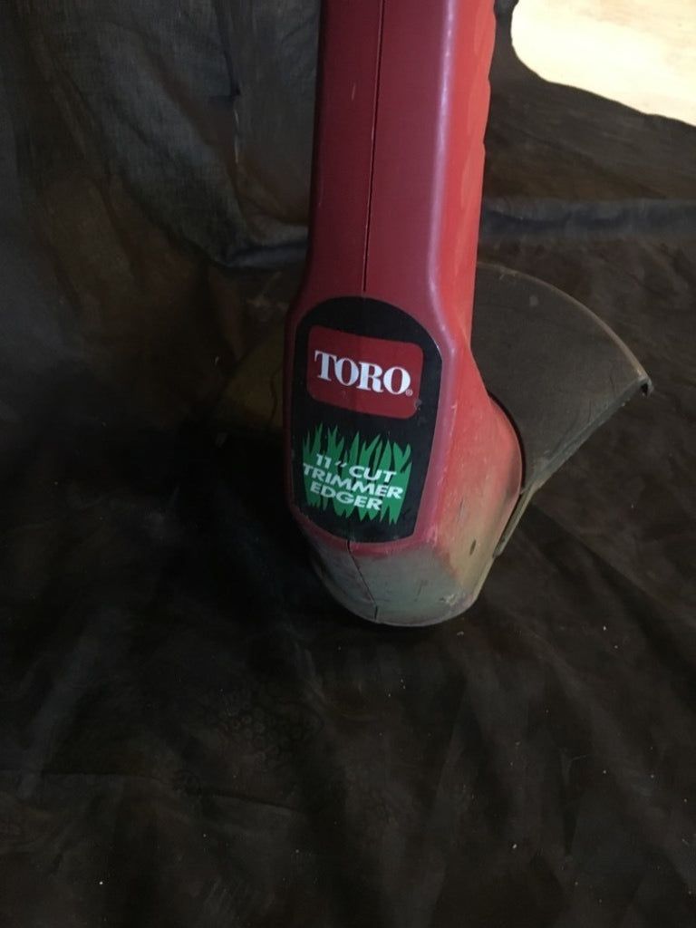 2. Close-up of Toro Cut Trimmer/Edger electric tool branding on the lower red housing, part of the tools category.  