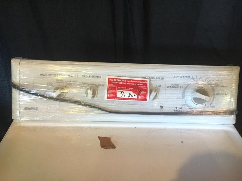 2. Close-up of Kenmore washer's control panel with service sticker and plastic wrap for transport.