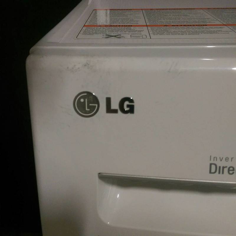 Close-up of the LG logo and detergent drawer on the WM1377HW front load washer, white appliance.  