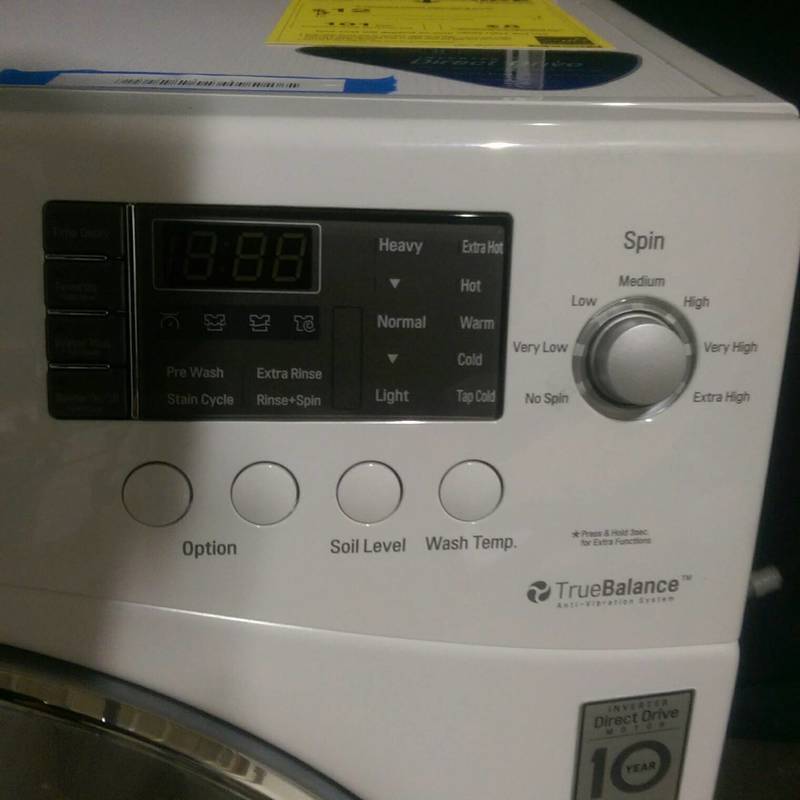 Control panel of the LG WM1377HW washer showing digital display, wash settings, and spin speed knob.