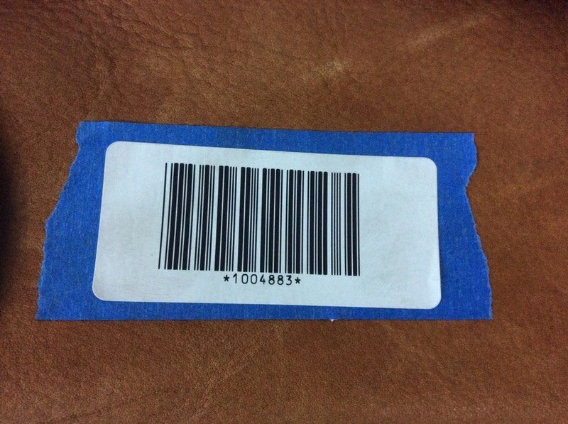 3. Close-up of a barcode label with the number 1004883, attached to brown Reperch luggage.