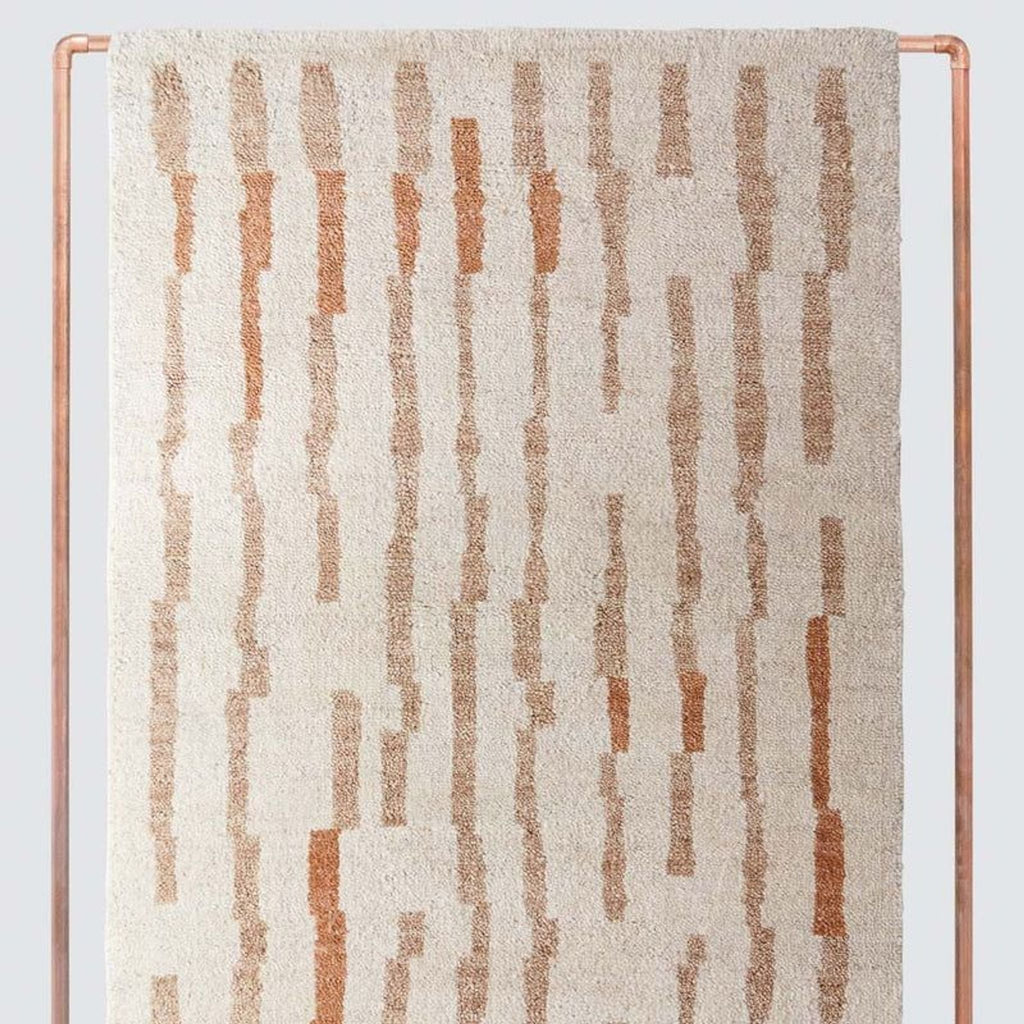 2. Close-up of a plush Citizenry rug showing vertical abstract tan and rust lines on a cream wool background.