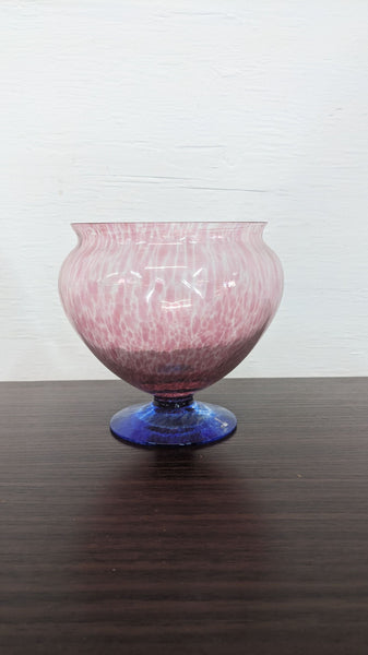 Pink glass vase with a blue base, featuring a wavy, textured pattern, by Reperch, on a dark surface.