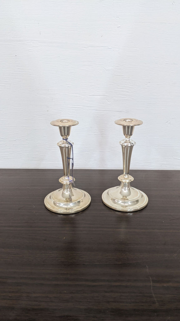 Pair of elegant silver candlesticks displayed on a wooden table.