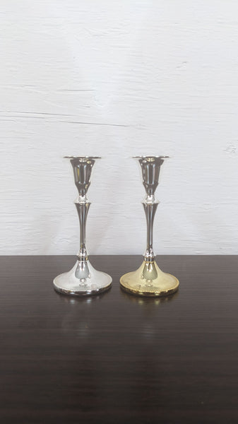Two elegant Reperch candle holders, silver and gold, on a dark surface.