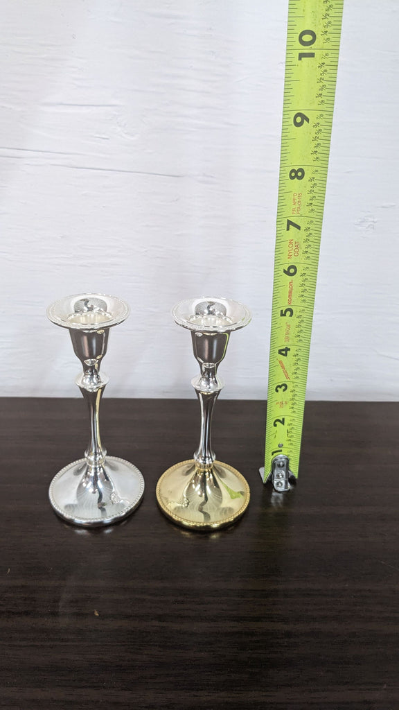Two Reperch candle holders with a measuring tape showing their height.