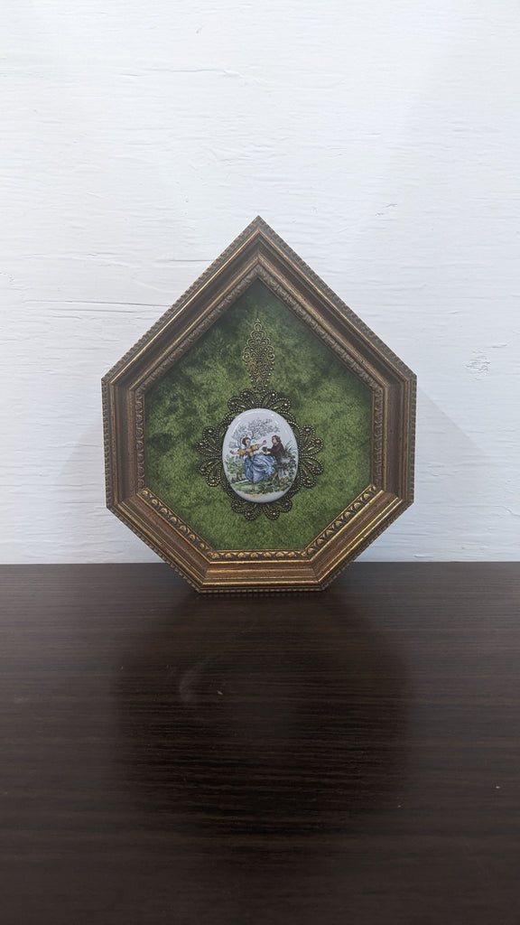 Pentagon-shaped frame with a vintage illustration on green fabric, featuring ornate borders.