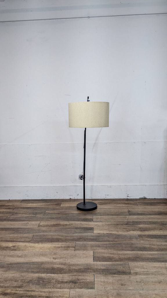 Reperch floor lamp with a straight arm and beige shade, standing on a wooden floor.