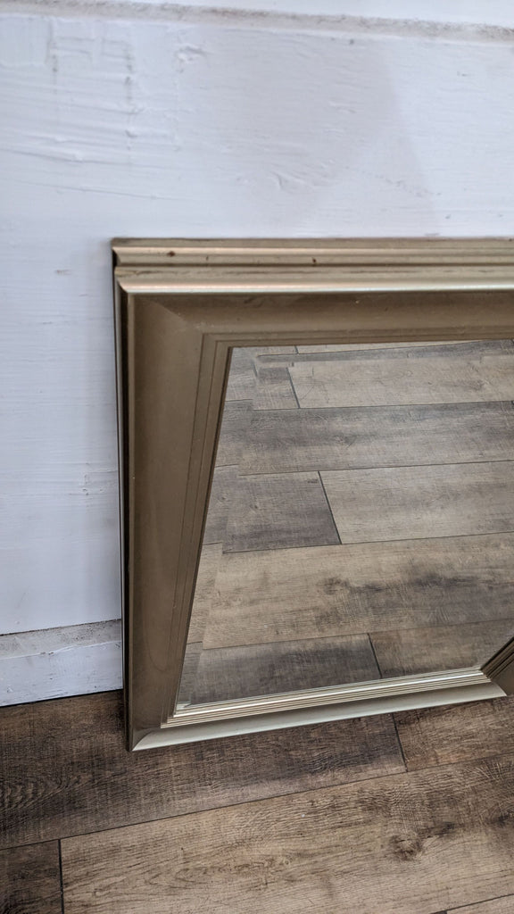 Close-up of Reperch beveled mirror with gold frame on wood.
