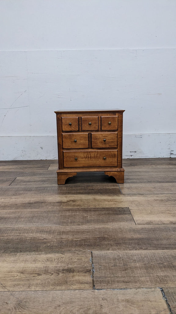 Front view of an Ethan Allen wooden end table with six drawers.