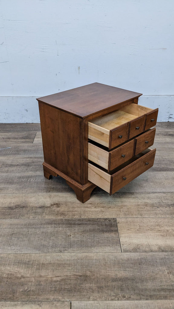 Side view of an Ethan Allen wooden end table with some drawers open.