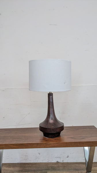 Reperch table lamp with a wooden base and white shade on a wooden table.