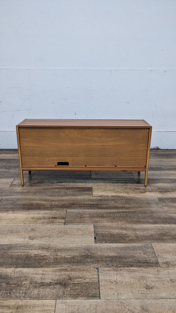 Back view of natural brown TV stand on wood floor.