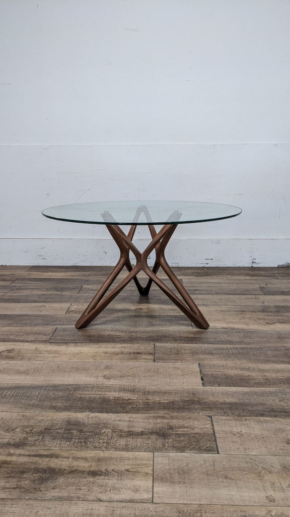 Scandinavian dining set with a round glass table and wooden cross base.