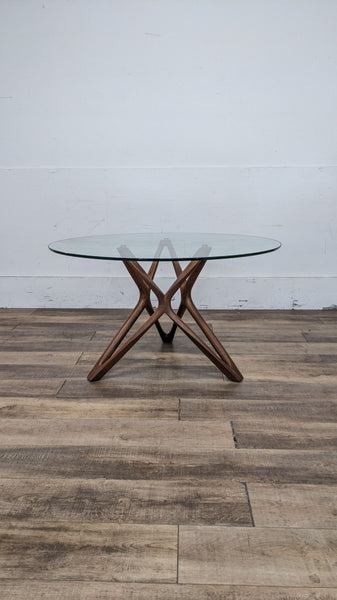 Scandinavian dining set with a round glass table and wooden cross base.