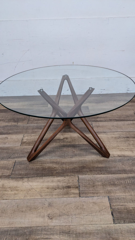 Round glass top dining table with a stylish wooden base for modern dining rooms.