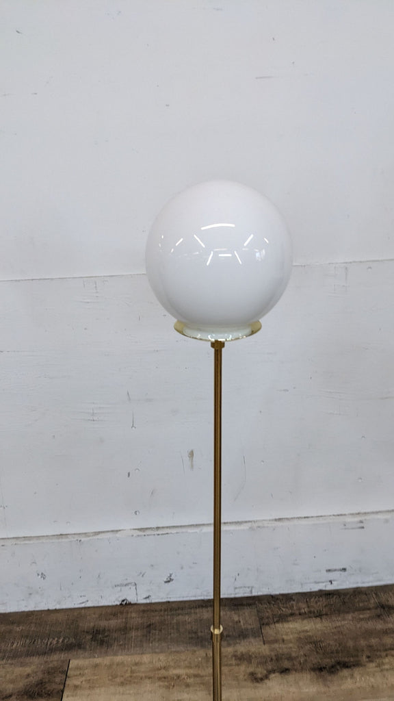 Close-up of the white globe lamp shade on a gold stand by Reperch.