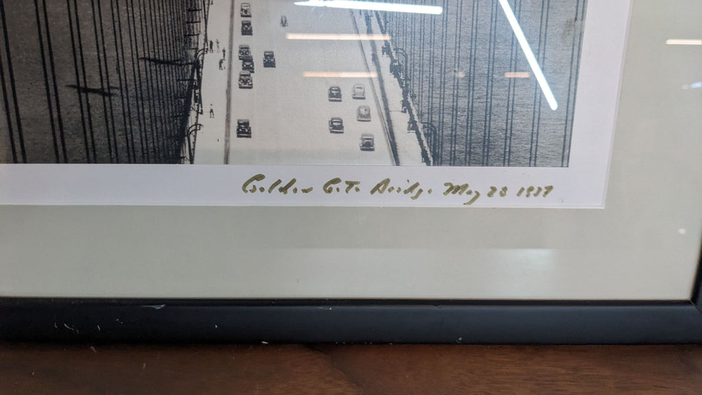 Close-up of the 1937 Golden Gate Bridge photo in a black frame, showing signature.