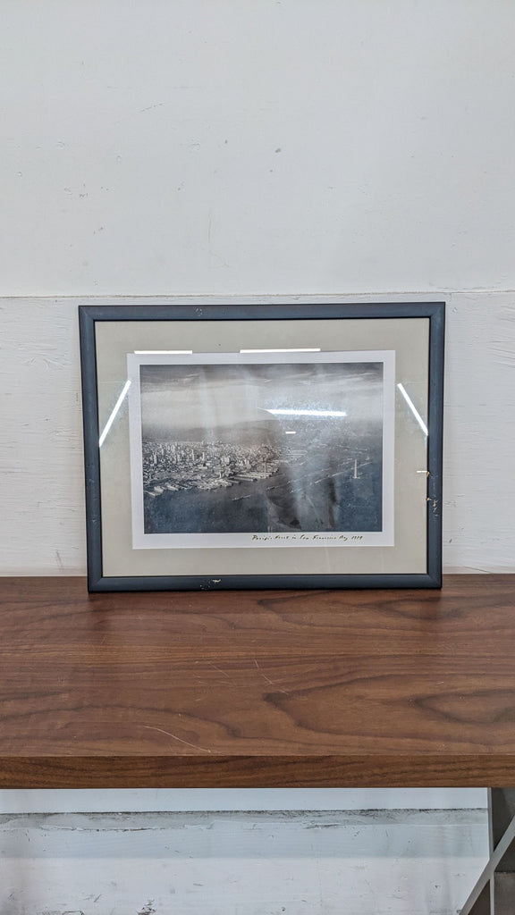 Framed black and white photo of San Francisco Bay from 1934 on a wooden shelf.