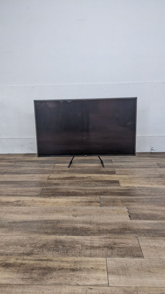LG flat-screen TV on a wooden floor, showcasing a sleek design and slim profile.
