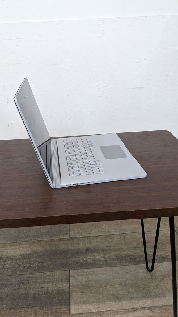 Microsoft Surface device on a wooden table with a white background.