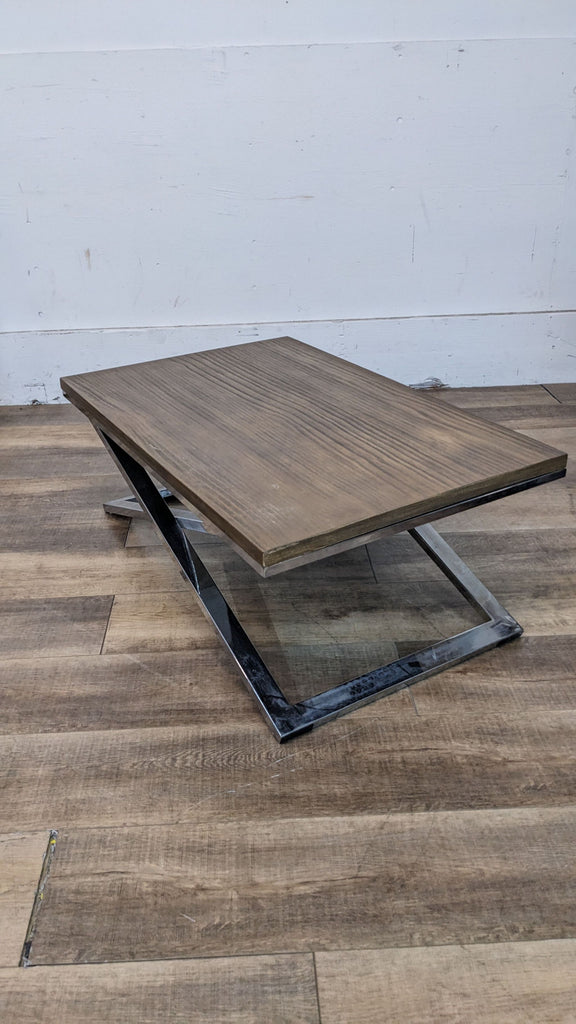 Cost Plus metal X base coffee table with a wooden top, showing signs of missing screws and tarnished metal.