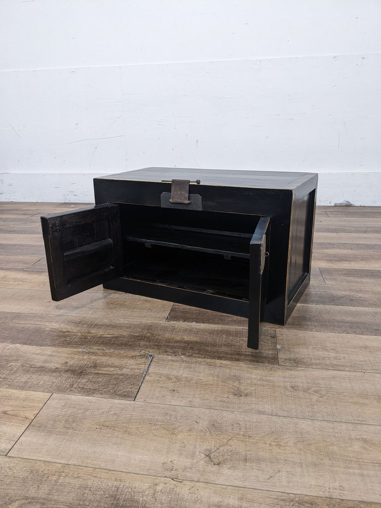 a black lacquer coffee table with a metal drawer and a brass lock.