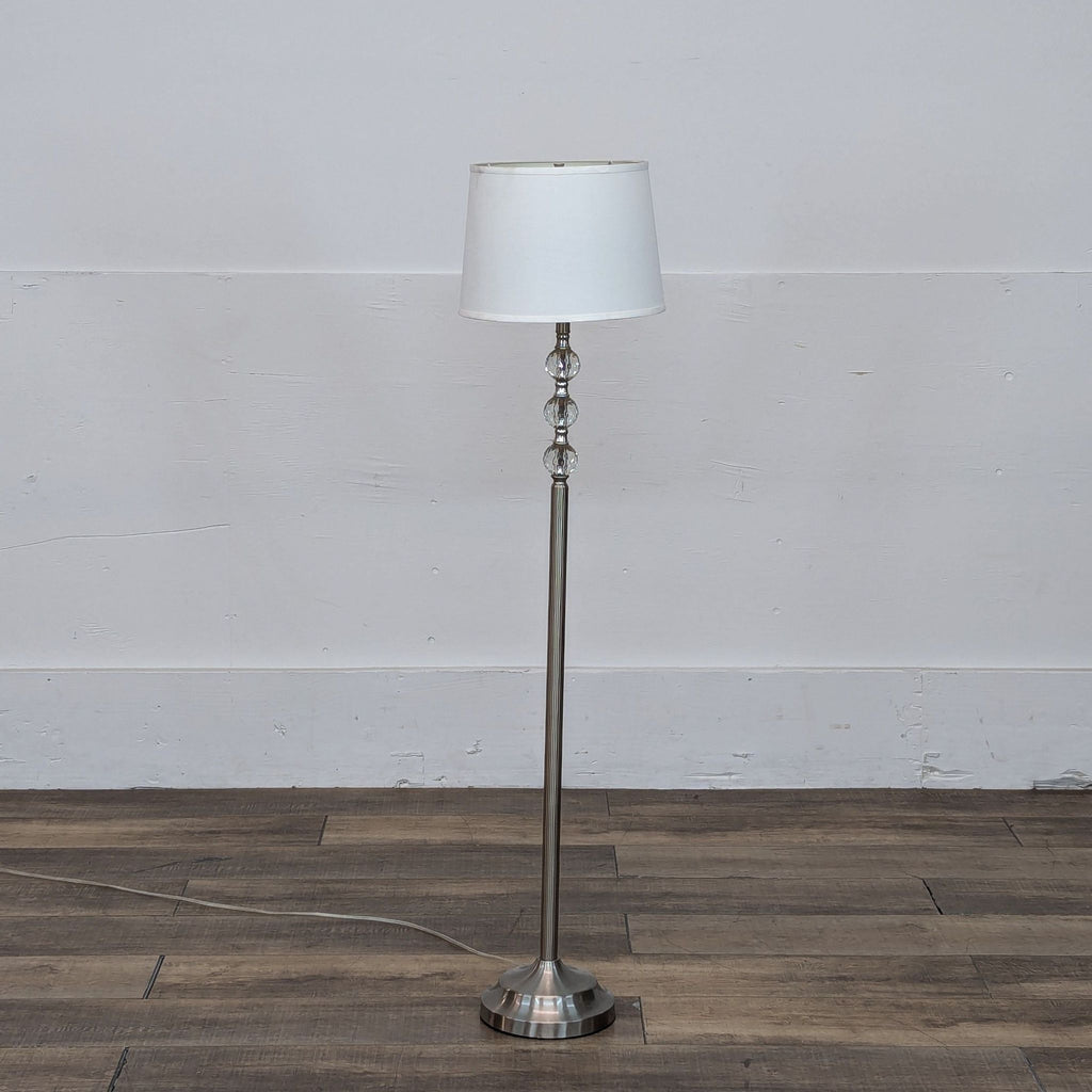 Reperch floor lamp with white shade on wood floor background.
