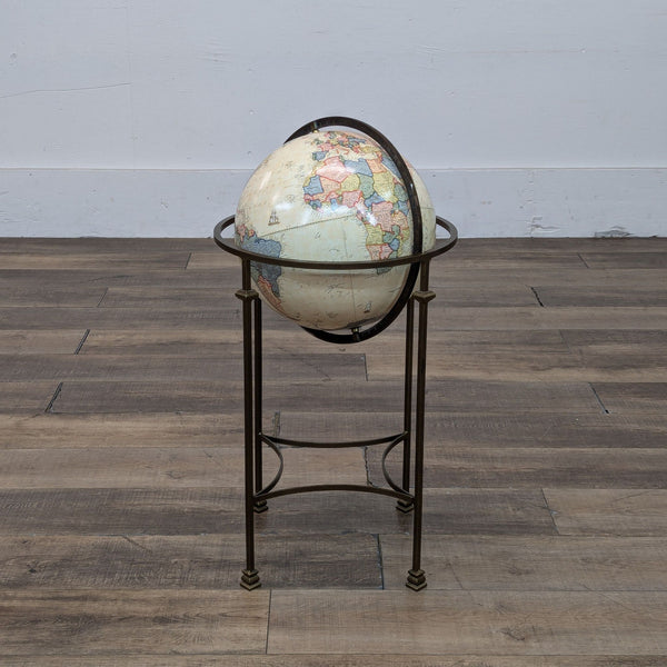 Vintage-style globe on a metal stand, placed on wooden floor.