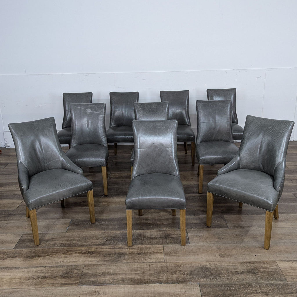Gray leather dining chairs with nailhead trim on wooden floor.