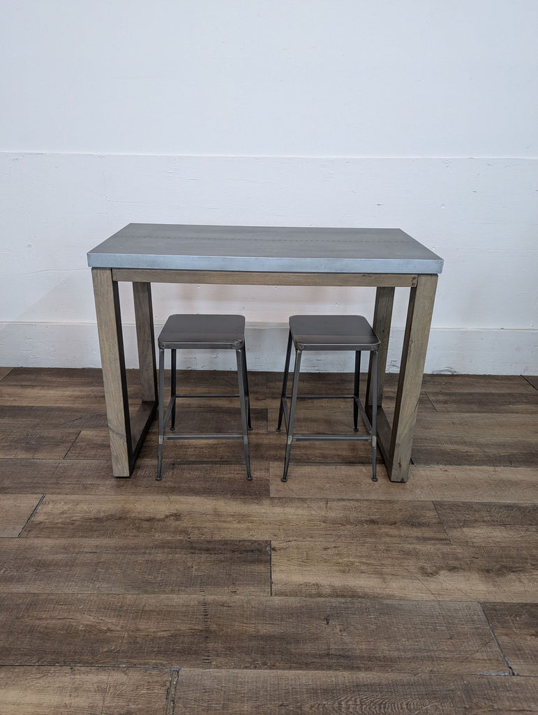Dining set with a sleek gray tabletop and matching stools on a wooden floor.