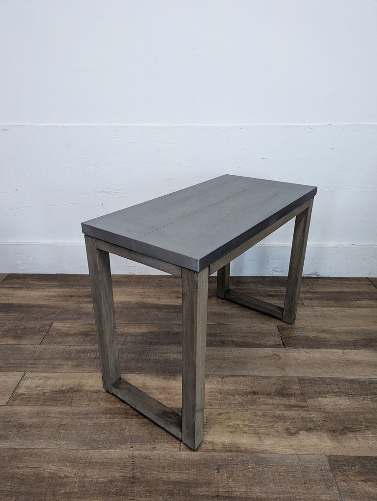 Side view of a modern dining bench with gray top and wooden frame.