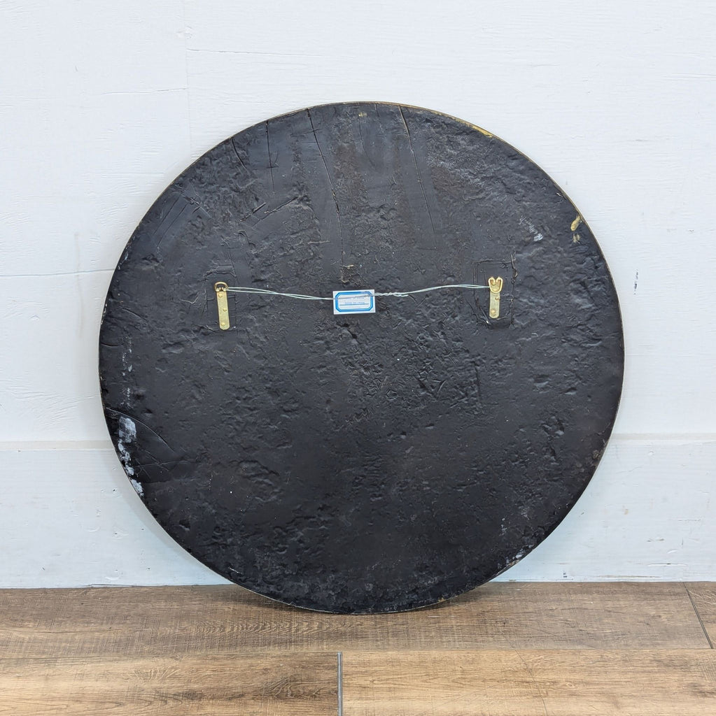 3. Back of a Reperch round wall art showing a black textured surface with attached hanging hardware.
