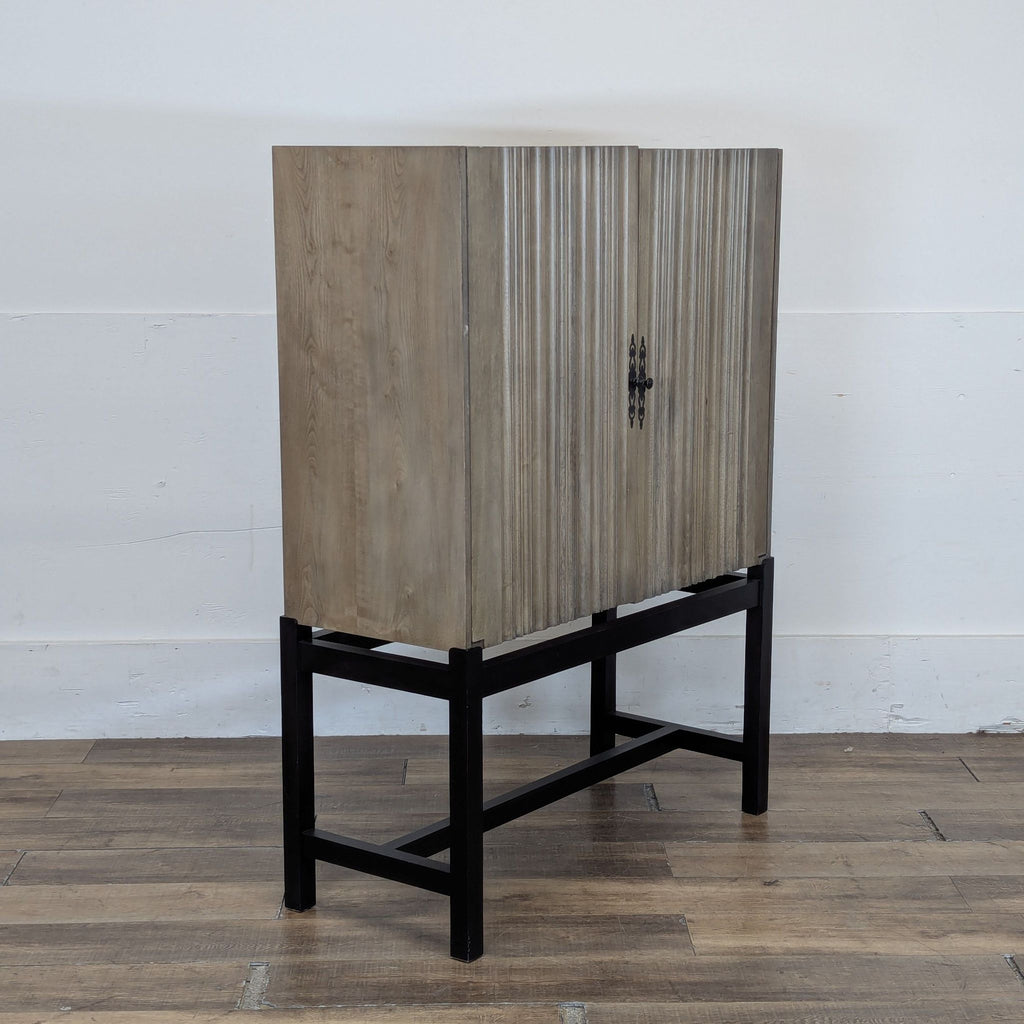 3. Angled side view of Reperch ribbed wood cabinet, highlighting the textured doors and metal base.