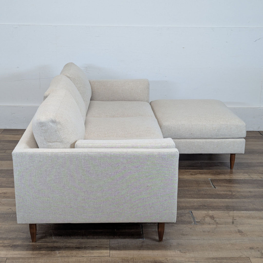 2. Side view of a BenchMade Modern sectional, featuring slim arms, Merrick fabric, and walnut tapered legs.