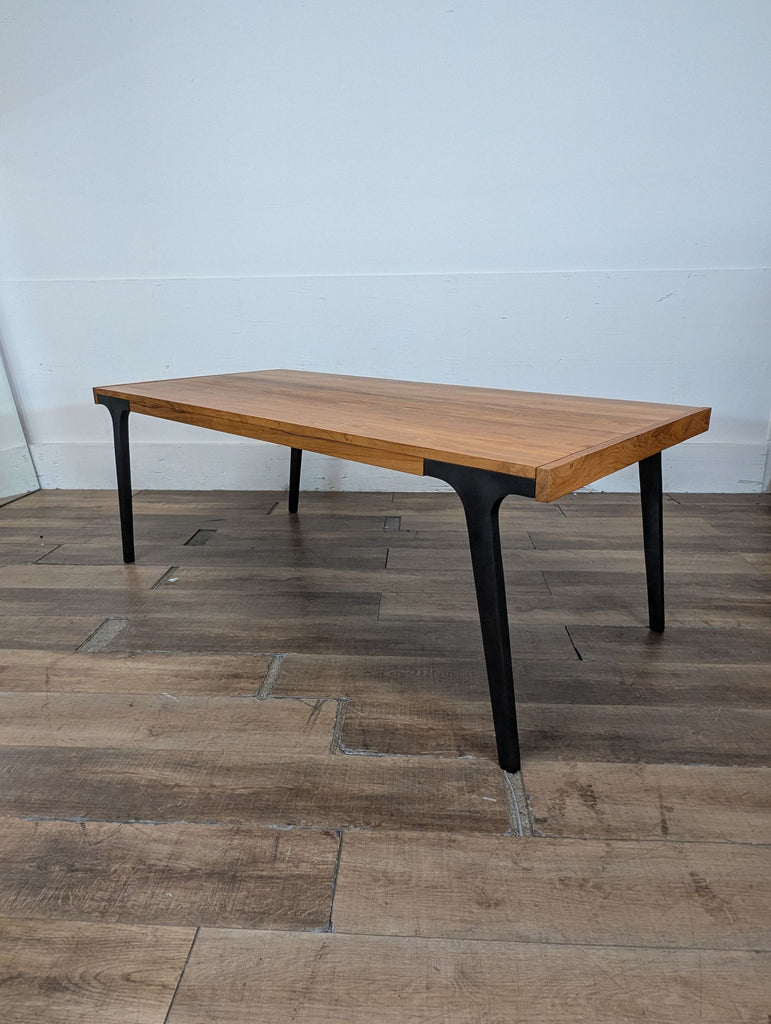 1. Rectangular Crate & Barrel dining table with a natural wood top and black metal legs on wood flooring.