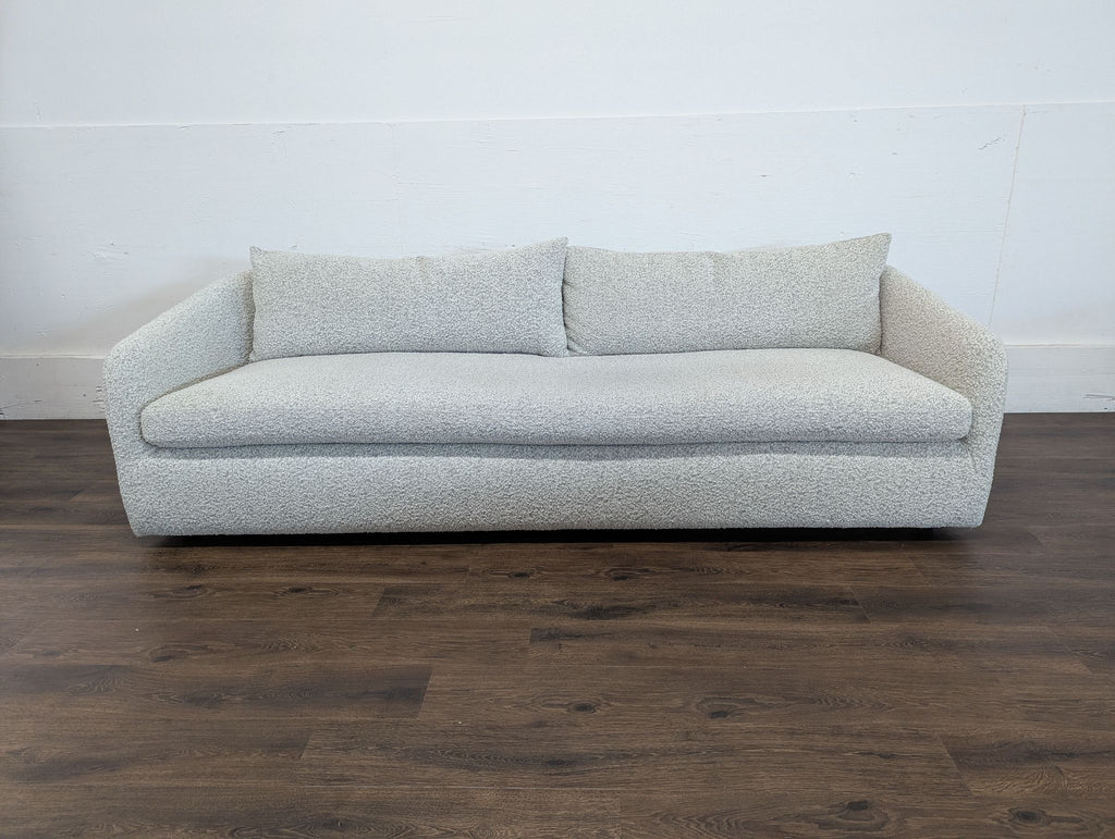 3. Three-seat Reperch sofa in a neutral textured fabric, with two large back cushions and curved armrests, on wood floor.