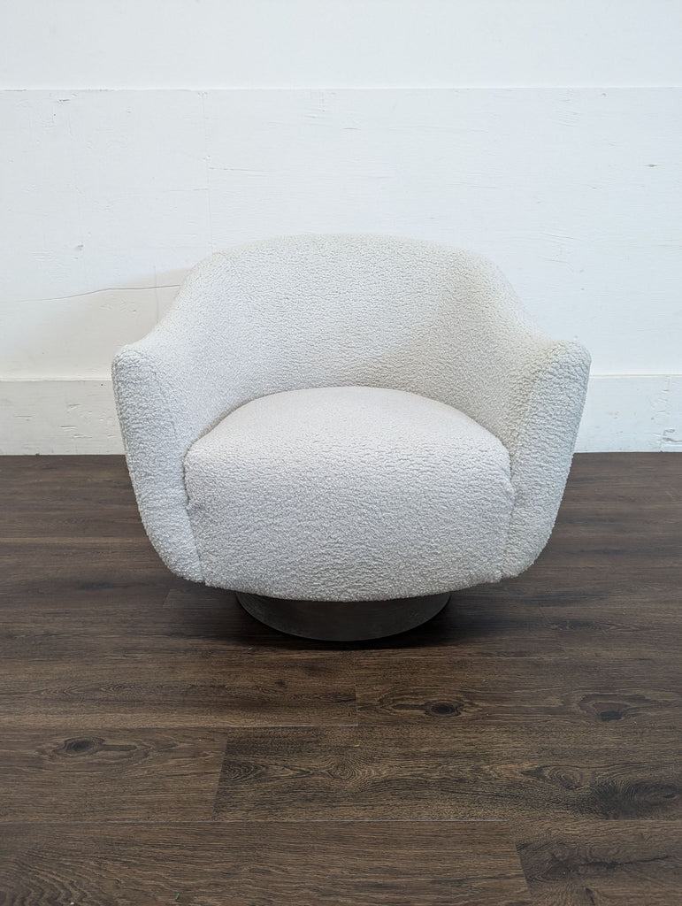 2. Interlude Home lounge chair with textured white upholstery and curved arms, positioned on a dark wood floor.