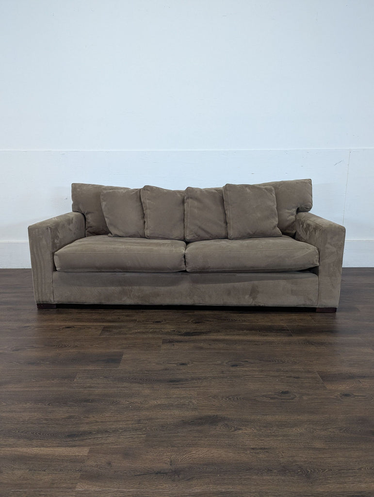 3. Crate and Barrel 3-seat taupe couch with cushions, shown against a white wall and dark wood floor.