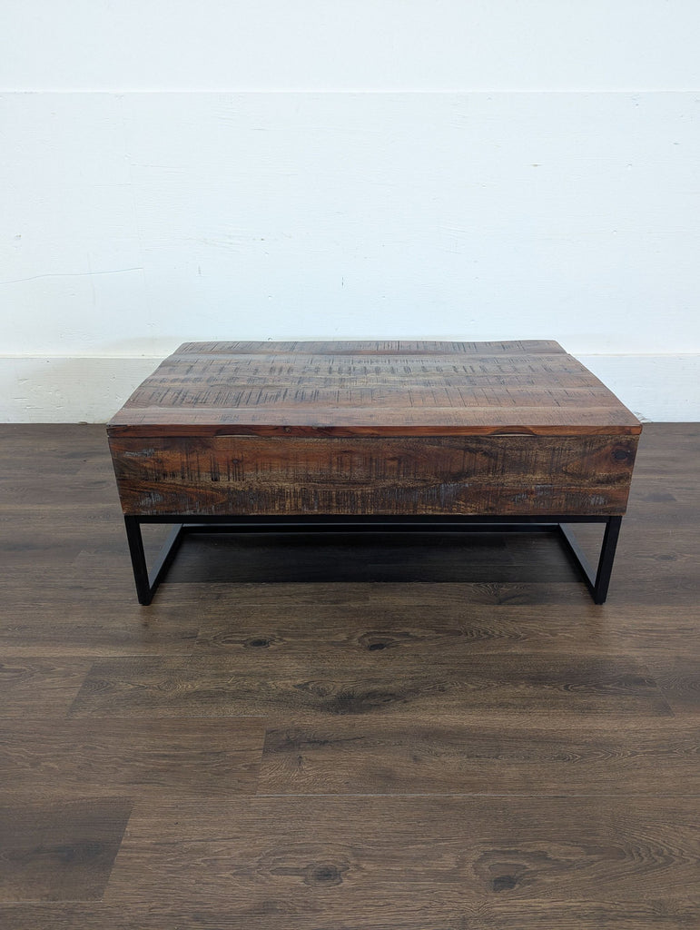 3. Coffee table from coffee table brand, front view showing thick wooden slab design and metal base on wooden flooring.