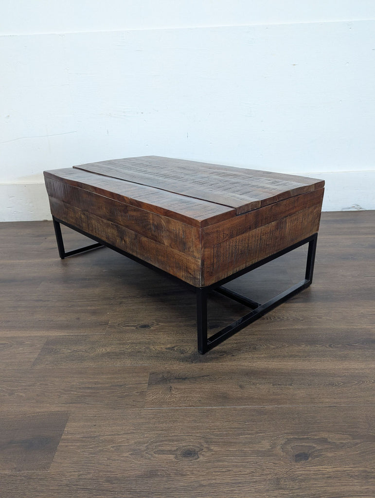 2. Rectangular coffee table by coffee table brand with a solid wood top and black metal legs against a plain wall.
