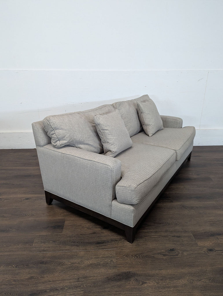 3. Angled view of an Ethan Allen 3-seat sofa, showing light beige upholstery, three cushions, and dark wood legs.