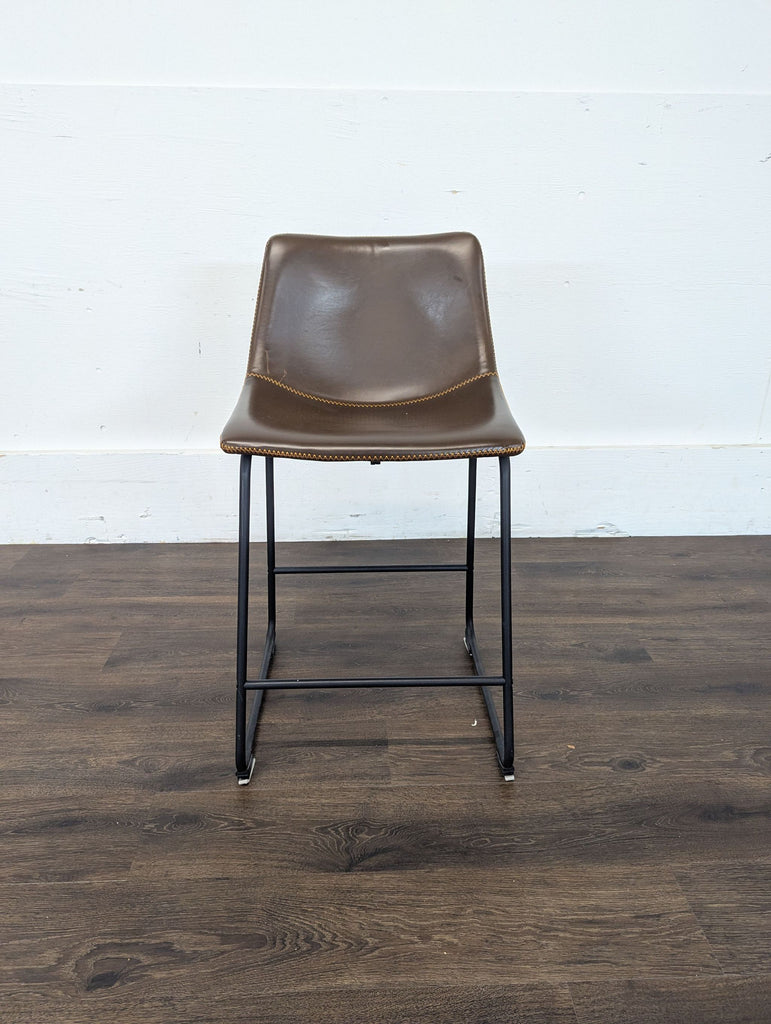 2. Single Reperch bar stool with brown seat and black metal frame, displayed against a white wall and dark wood floor.  