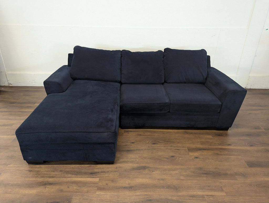 2. Two-year-old blue sectional couch shown on a wooden floor, featuring plush seats and wide arms.